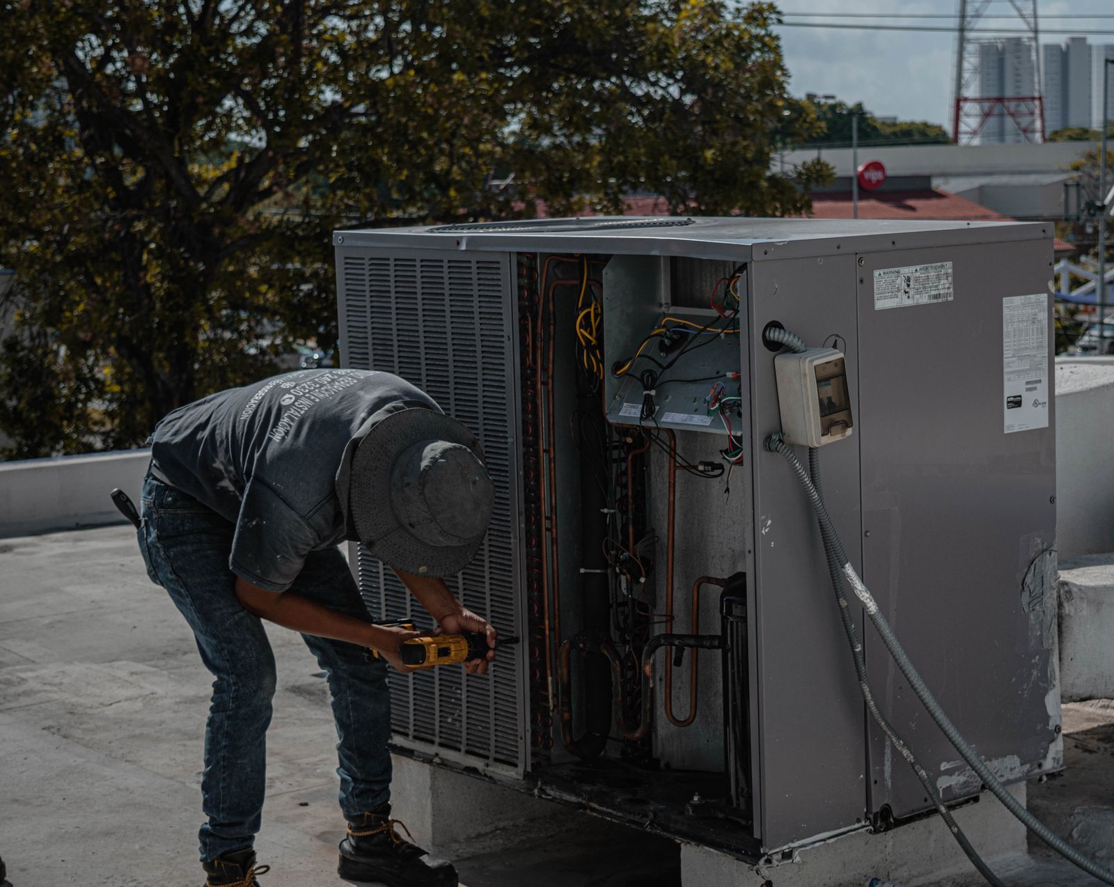 Technician repairing an outdoor air conditioner unit with a manifold gauge