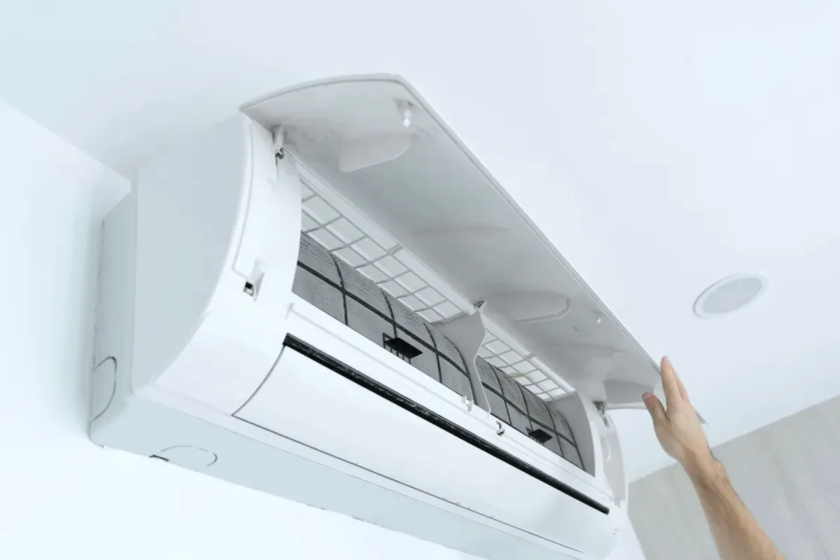 Hand opening the cover of a wall-mounted ductless air conditioner